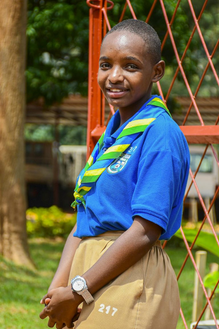 A young Rwandan scout in uniform smiles while posing outdoors, Southern Province, Rwanda.